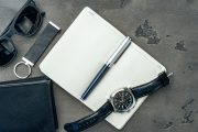 Businessman's accessories including notepad, watch and purse on dark grey background